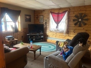 carpeted living room featuring a paneled ceiling and wooden walls