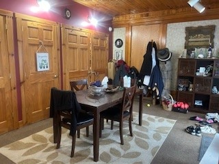 dining space with light carpet, wood walls, and wooden ceiling