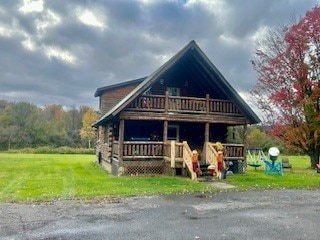 log cabin with a front lawn and a balcony