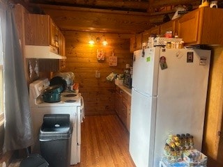 kitchen featuring light hardwood / wood-style flooring, white appliances, and wood walls