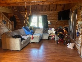 living room with hardwood / wood-style flooring, beamed ceiling, and rustic walls