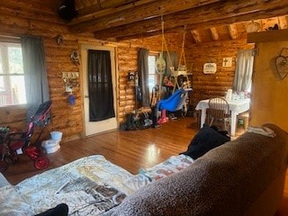 living room featuring beamed ceiling, rustic walls, and wood-type flooring