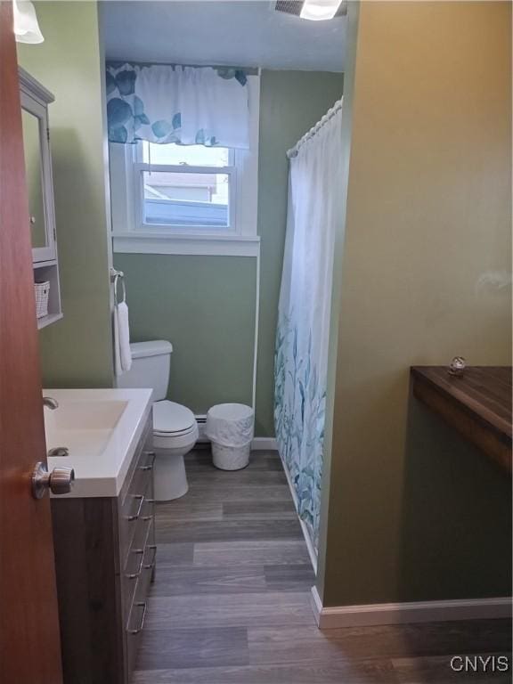 full bathroom with toilet, baseboards, wood finished floors, and vanity