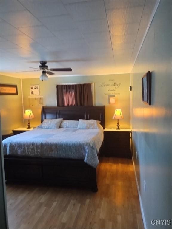 bedroom with dark wood-style floors, ceiling fan, and baseboards