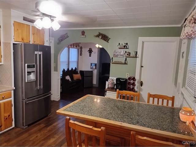 kitchen with stainless steel fridge, arched walkways, crown molding, dark wood-type flooring, and a breakfast bar