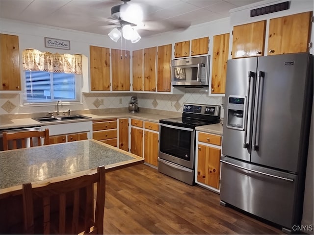 kitchen with stainless steel appliances, brown cabinetry, a sink, and light countertops