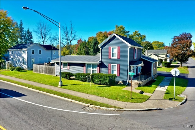 view of front facade with a residential view, metal roof, fence, and a front yard