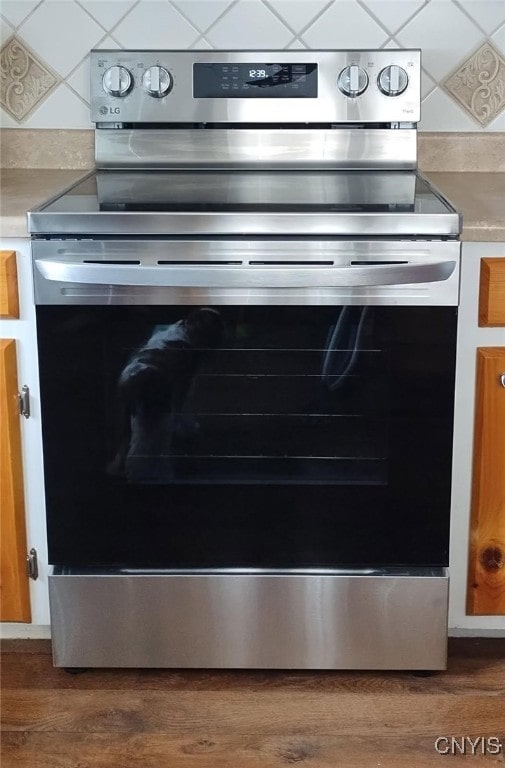 details featuring light countertops, electric range, wood finished floors, and tasteful backsplash