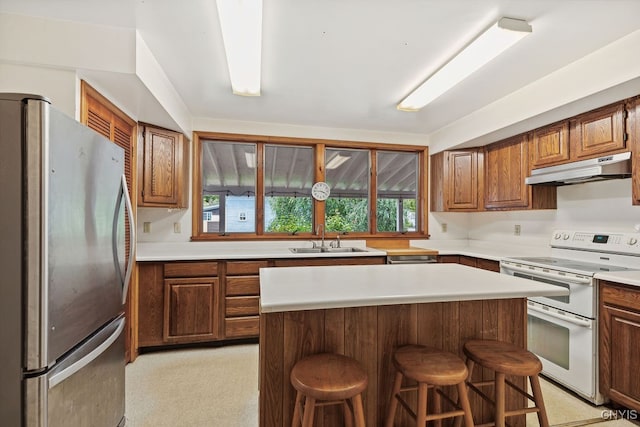 kitchen with stainless steel fridge, a kitchen island, a kitchen bar, and white range oven