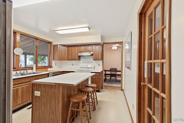 kitchen with a kitchen island, dishwasher, a breakfast bar area, white electric range, and sink