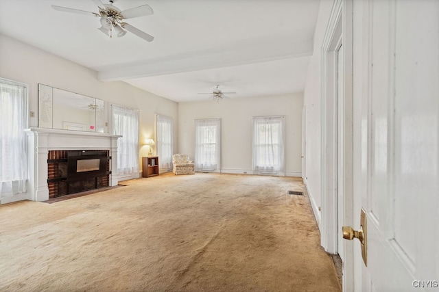 unfurnished living room featuring a fireplace, beamed ceiling, carpet, and ceiling fan