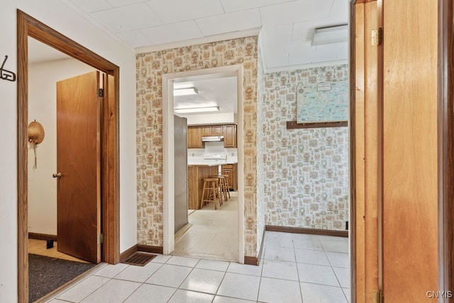 hallway featuring ornamental molding and light tile patterned flooring