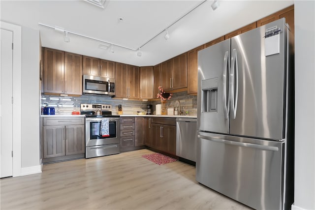 kitchen with sink, decorative backsplash, appliances with stainless steel finishes, and light wood-type flooring