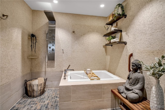 bathroom with a relaxing tiled tub and tile walls