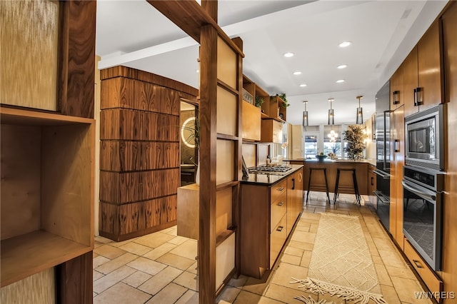 kitchen featuring appliances with stainless steel finishes, kitchen peninsula, and decorative light fixtures