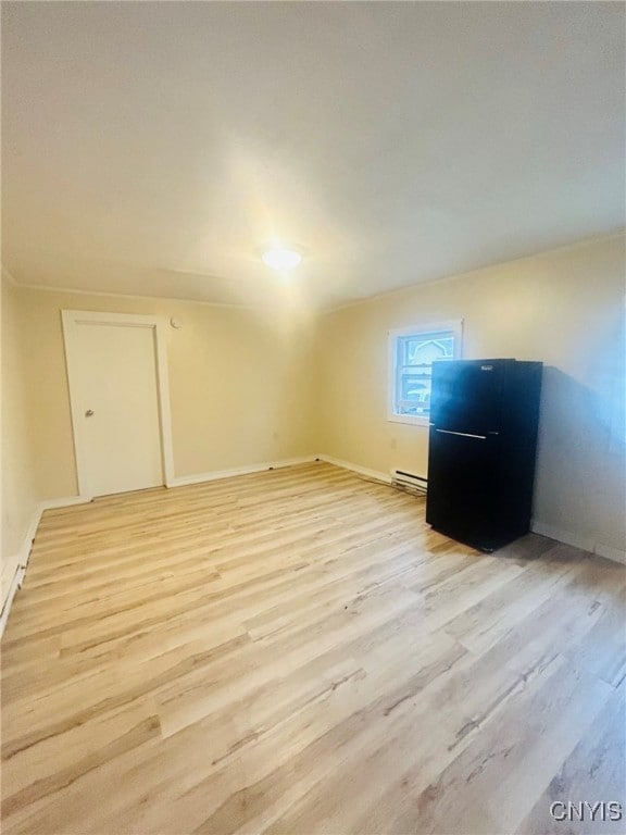 unfurnished room featuring light hardwood / wood-style flooring and a baseboard heating unit