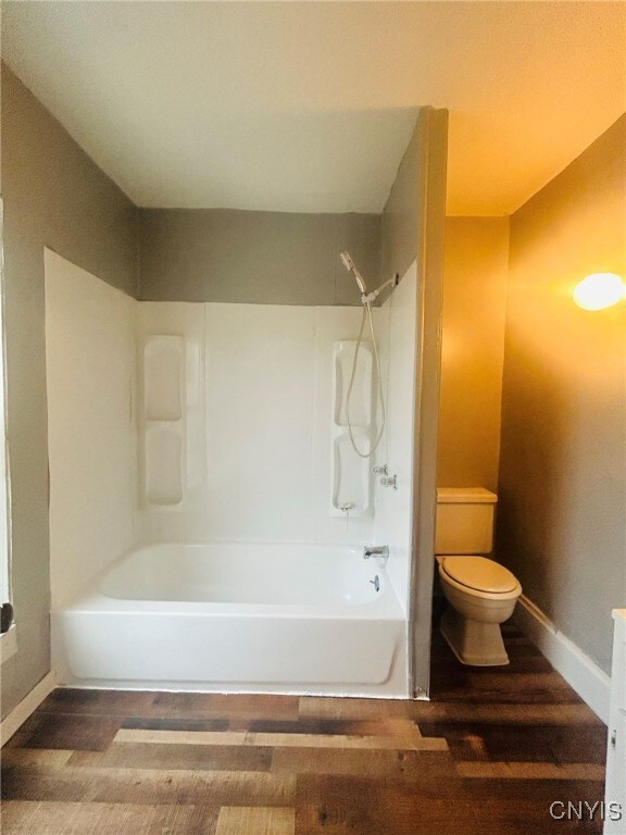 bathroom featuring  shower combination, hardwood / wood-style flooring, and toilet