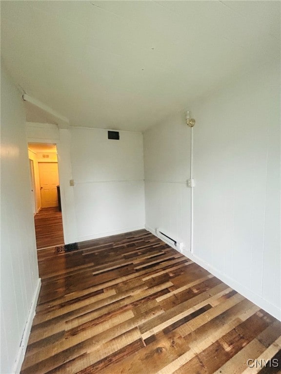 spare room with a baseboard heating unit and dark wood-type flooring