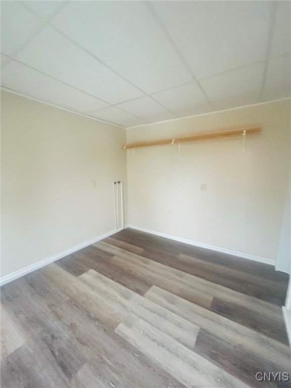 spare room with a paneled ceiling and wood-type flooring