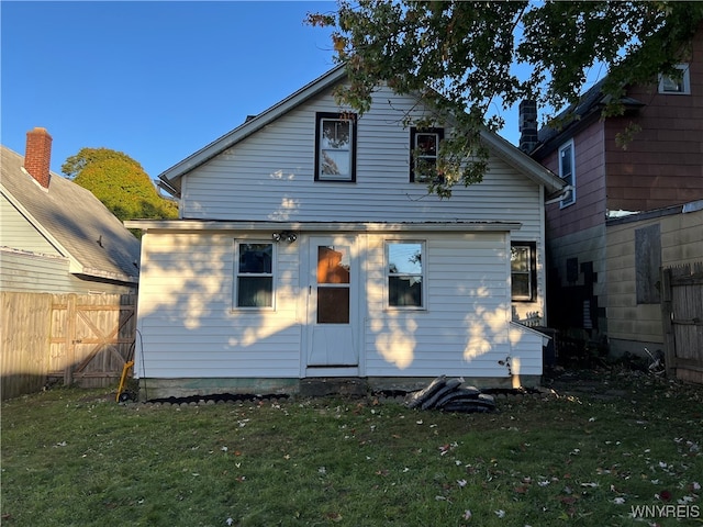 rear view of property with a lawn and fence