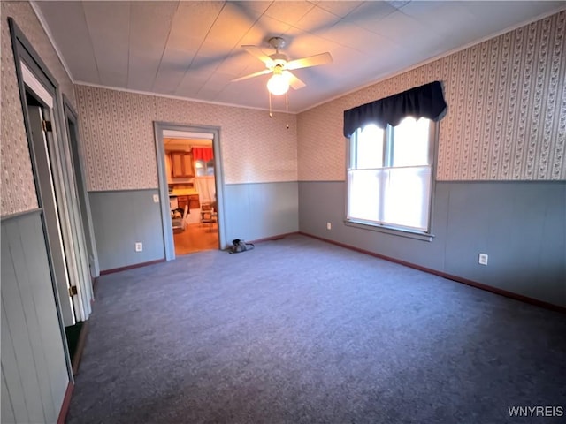 unfurnished bedroom featuring carpet floors, crown molding, wainscoting, ceiling fan, and wallpapered walls