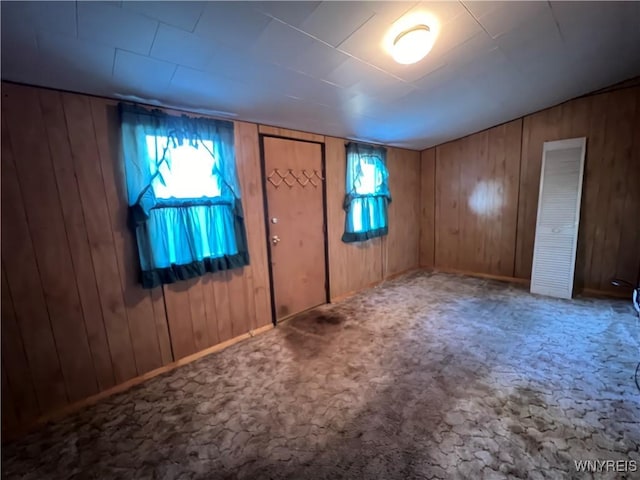 carpeted foyer featuring wood walls