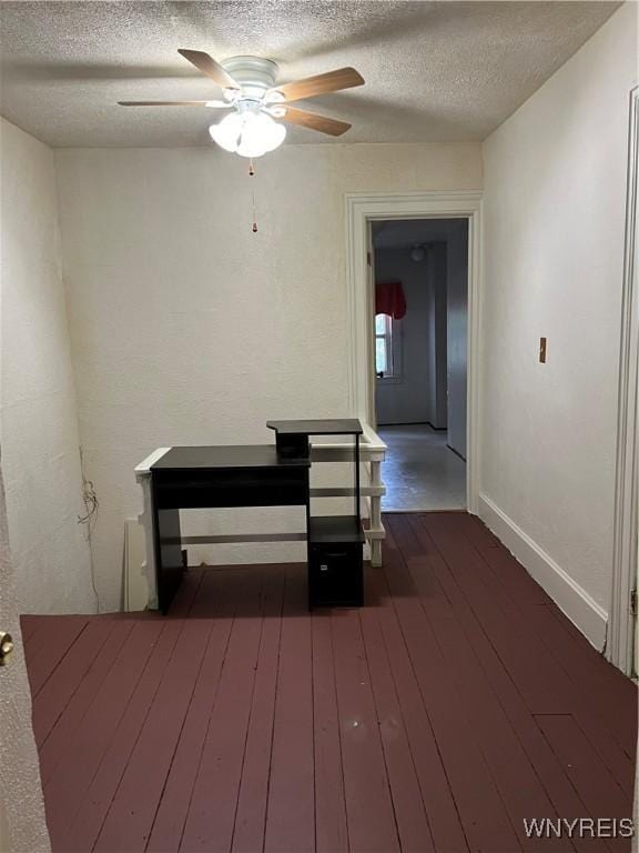 hall featuring dark wood-style floors, a textured ceiling, and baseboards