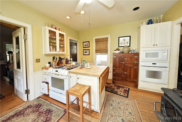 kitchen featuring white appliances, wooden counters, ceiling fan, light wood-type flooring, and white cabinetry