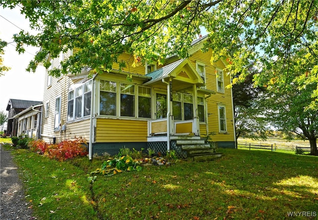 view of front of property featuring a sunroom and a front lawn