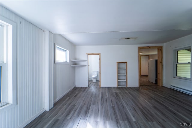 interior space with hardwood / wood-style floors, a baseboard heating unit, and wooden walls