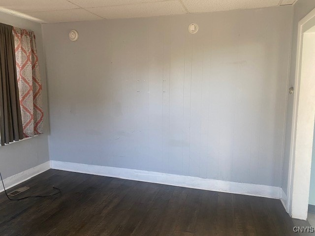 spare room with a drop ceiling and dark hardwood / wood-style floors