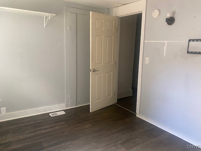 unfurnished room with dark wood-type flooring