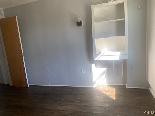 unfurnished room with dark wood-type flooring