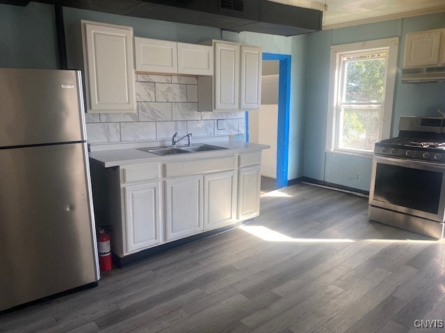 kitchen featuring appliances with stainless steel finishes, white cabinetry, hardwood / wood-style flooring, and sink