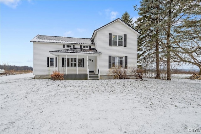 snow covered back of property featuring covered porch