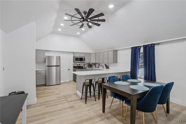 dining room with ceiling fan, light hardwood / wood-style floors, and vaulted ceiling