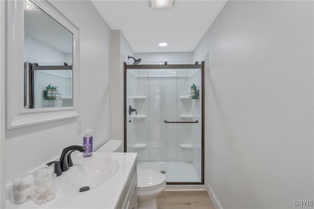 bathroom featuring walk in shower, hardwood / wood-style flooring, vanity, and toilet