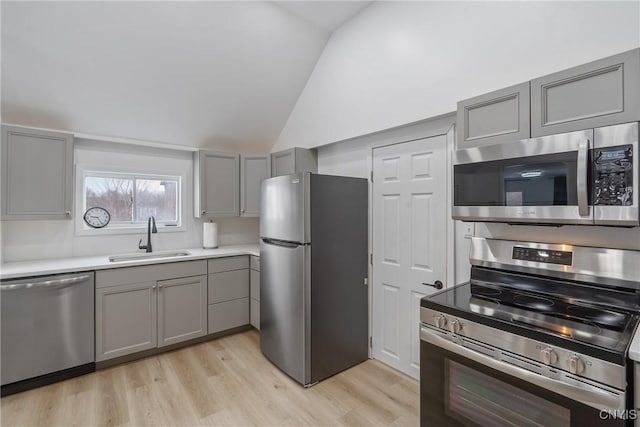 kitchen with lofted ceiling, sink, gray cabinets, appliances with stainless steel finishes, and light hardwood / wood-style floors