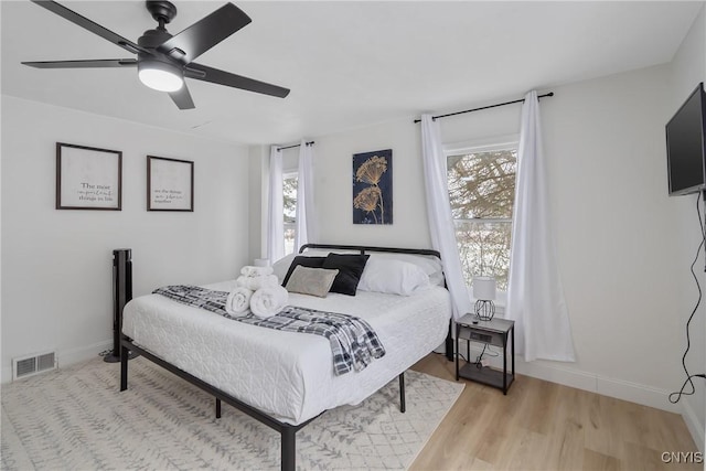 bedroom featuring light wood-type flooring, multiple windows, and ceiling fan