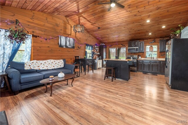 living room featuring lofted ceiling, wood ceiling, wooden walls, light hardwood / wood-style flooring, and sink