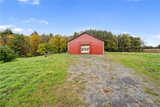 view of outbuilding with a rural view, a yard, and a garage