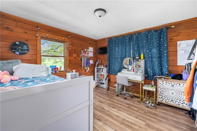 bedroom featuring wood-type flooring, a textured ceiling, and wooden walls