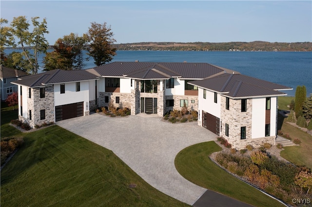 view of front of house featuring a garage, a front lawn, and a water view