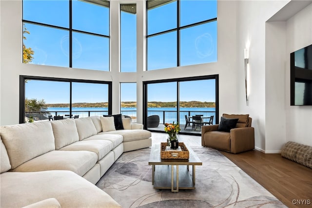 living room with a high ceiling, wood-type flooring, and a water view