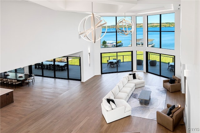 living room featuring a water view, hardwood / wood-style flooring, an inviting chandelier, and plenty of natural light