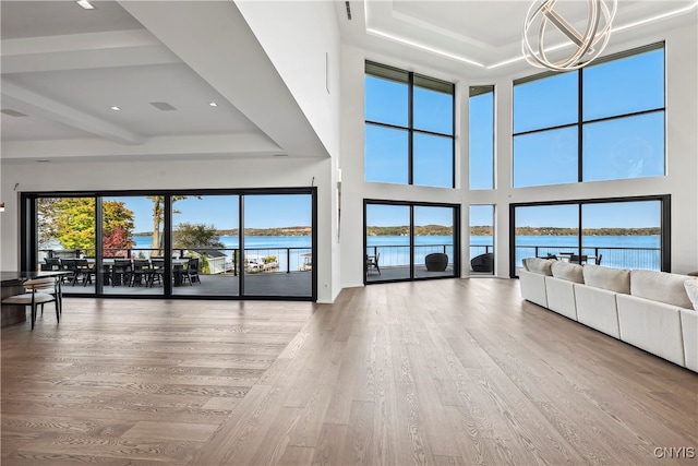 unfurnished living room with a water view, hardwood / wood-style flooring, and a raised ceiling