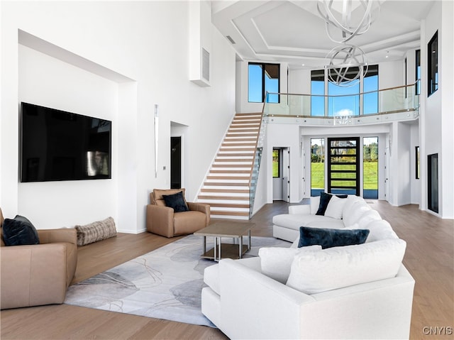 living room featuring a high ceiling, light hardwood / wood-style floors, and an inviting chandelier