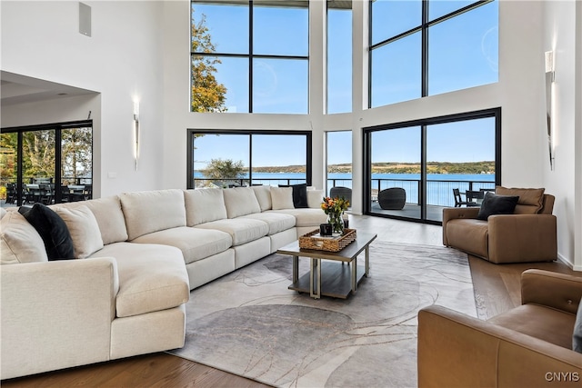 living room featuring a towering ceiling, plenty of natural light, and a water view