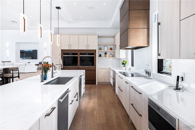 kitchen with dark wood-type flooring, hanging light fixtures, sink, black appliances, and light stone counters