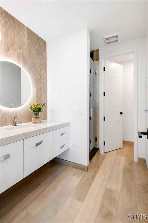 bathroom with vanity, walk in shower, and hardwood / wood-style floors